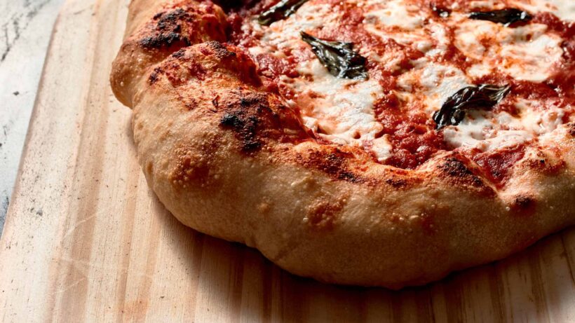 Close up of Neapolitan, Margherita pizza on a wooden peel.