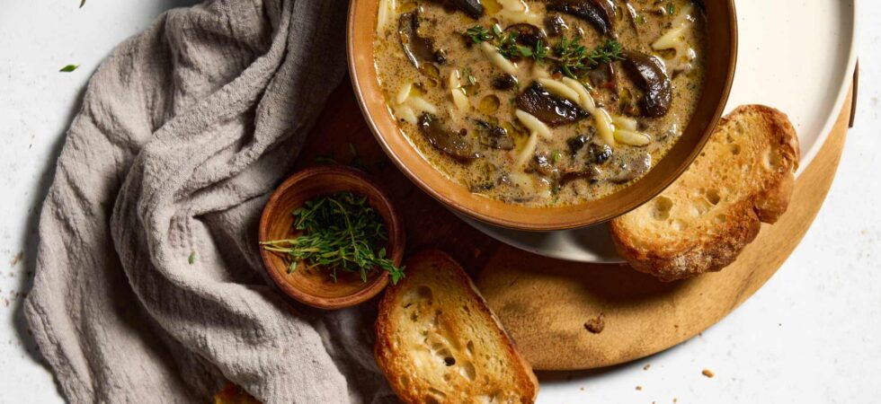 A bowl of cream of mushroom soup with crostini surrounding it.