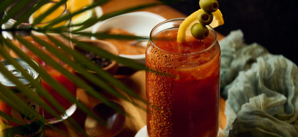 Bloody Mary Cocktail surrounded by ingredients and garnishes.