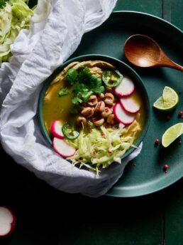 Top down view of Pozole verde topped with sliced radishes and jalapeños, shredded cabbage, and cilantro.