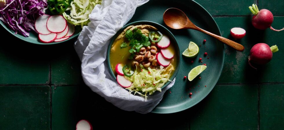 Top down view of Pozole verde topped with sliced radishes and jalapeños, shredded cabbage, and cilantro.