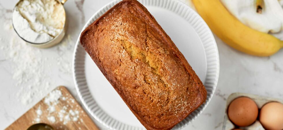 Banana bread loaf surrounded by ingredients