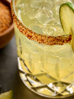 Close-up image of a pineapple, poblano margarita with a lime slice garnish.