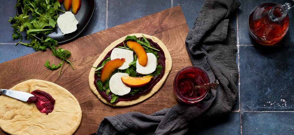 Preparing some roasted strawberry, beet, and goat cheese flatbreads for the oven.