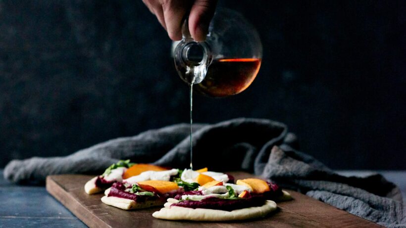 Drizzling white balsamic onto a roasted strawberry, beet, and goat cheese flatbread.