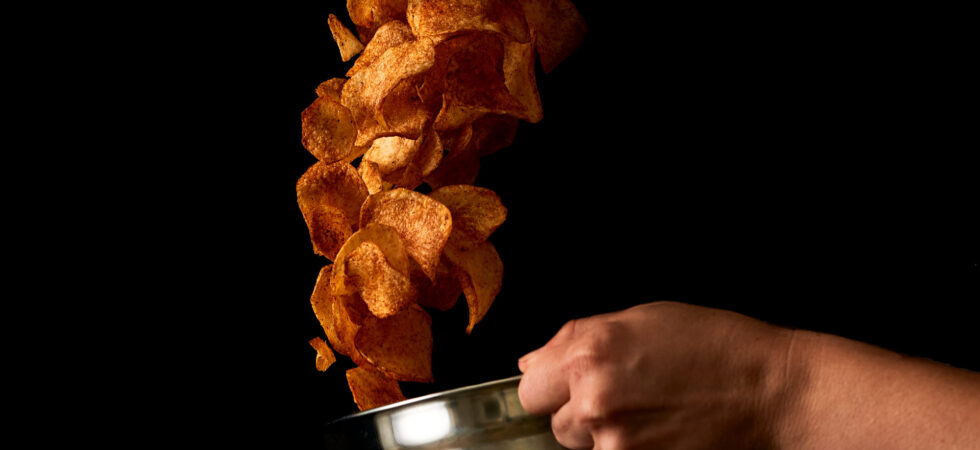 Tossing barbecue potato chips up out of a bowl.