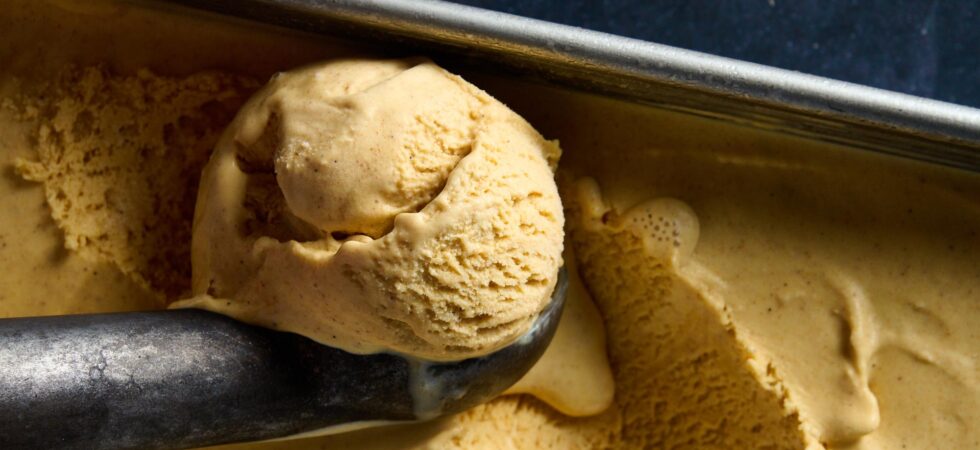 Scooping Browned Butter Bourbon Ice Cream from a metal contain with a vintage metal ice cream scoop.