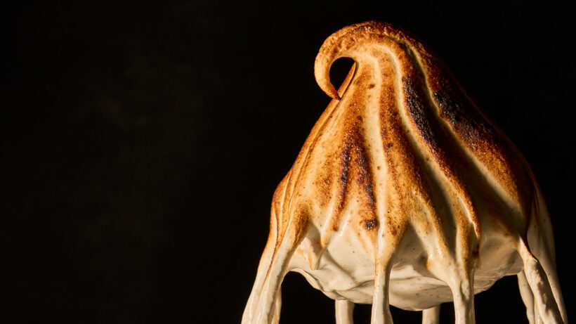 Medium-peaked, marshmallow fluff on the end of a whisk attachment that has been roasted.