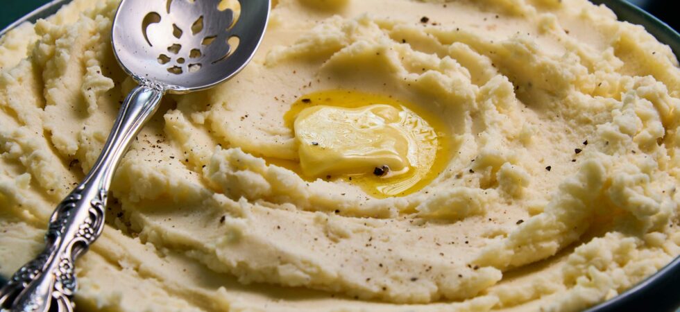 An up-close image of homestyle mashed potatoes with a melted pat of butter.