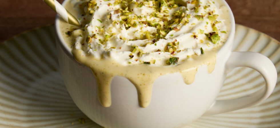 Pistachio-White Chocolate Milkshake in a coffee mug with whipped cream and chopped pistachios on top.