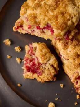 Close up of two cranberry-orange cream scones on a plate with one broken open to reveal the cranberry jam ribbon.