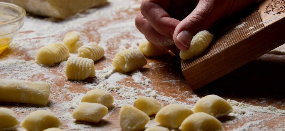 Rolling homemade potato gnocchi on a gnocchi board.