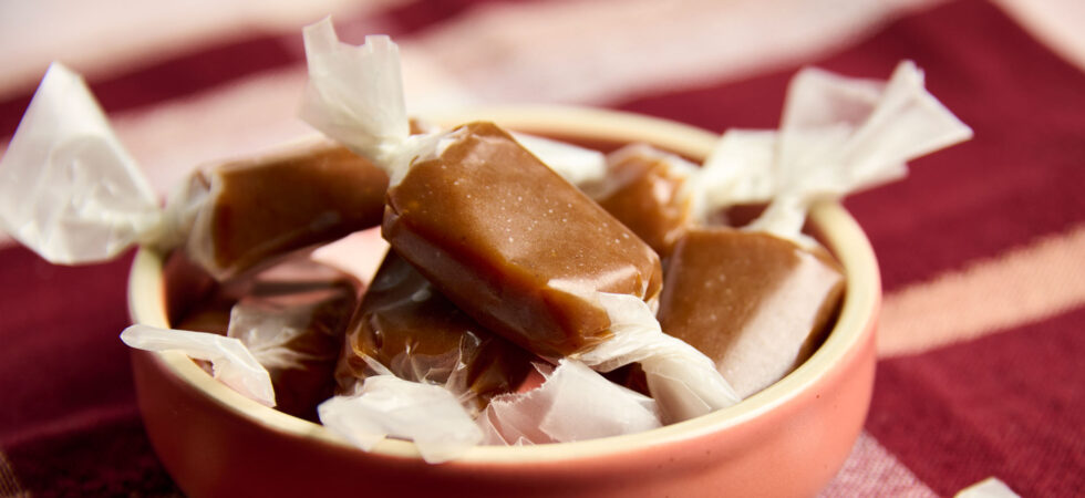 Apple Cider Caramel Candies wrapped in wax paper, piled into a bowl.