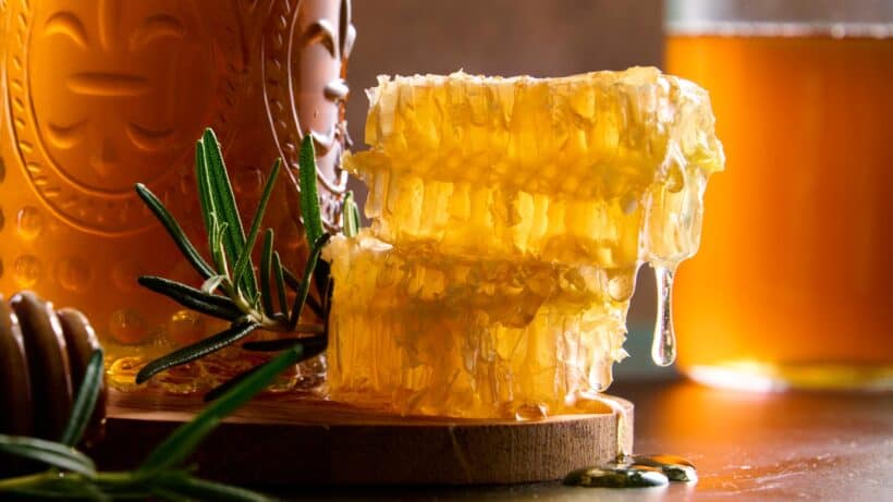 Honeycomb drip with freah rosemary and rosemary simple syrup bottle.