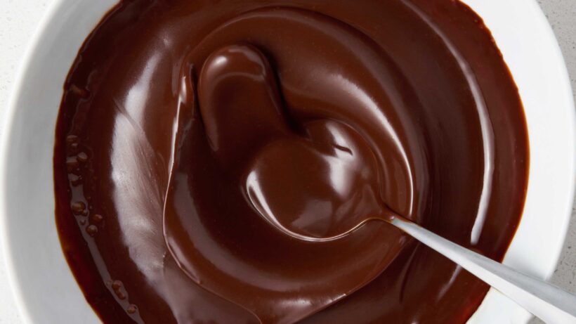Dark Chocolate Ganache Frosting warm and loose splashing in a bowl.