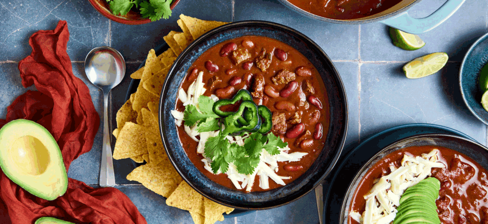Bowls of Chuck Roast Chili with toppings and sides.
